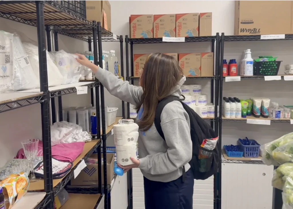 Student selecting hygiene products from a school pantry stocked by Giving the Basics